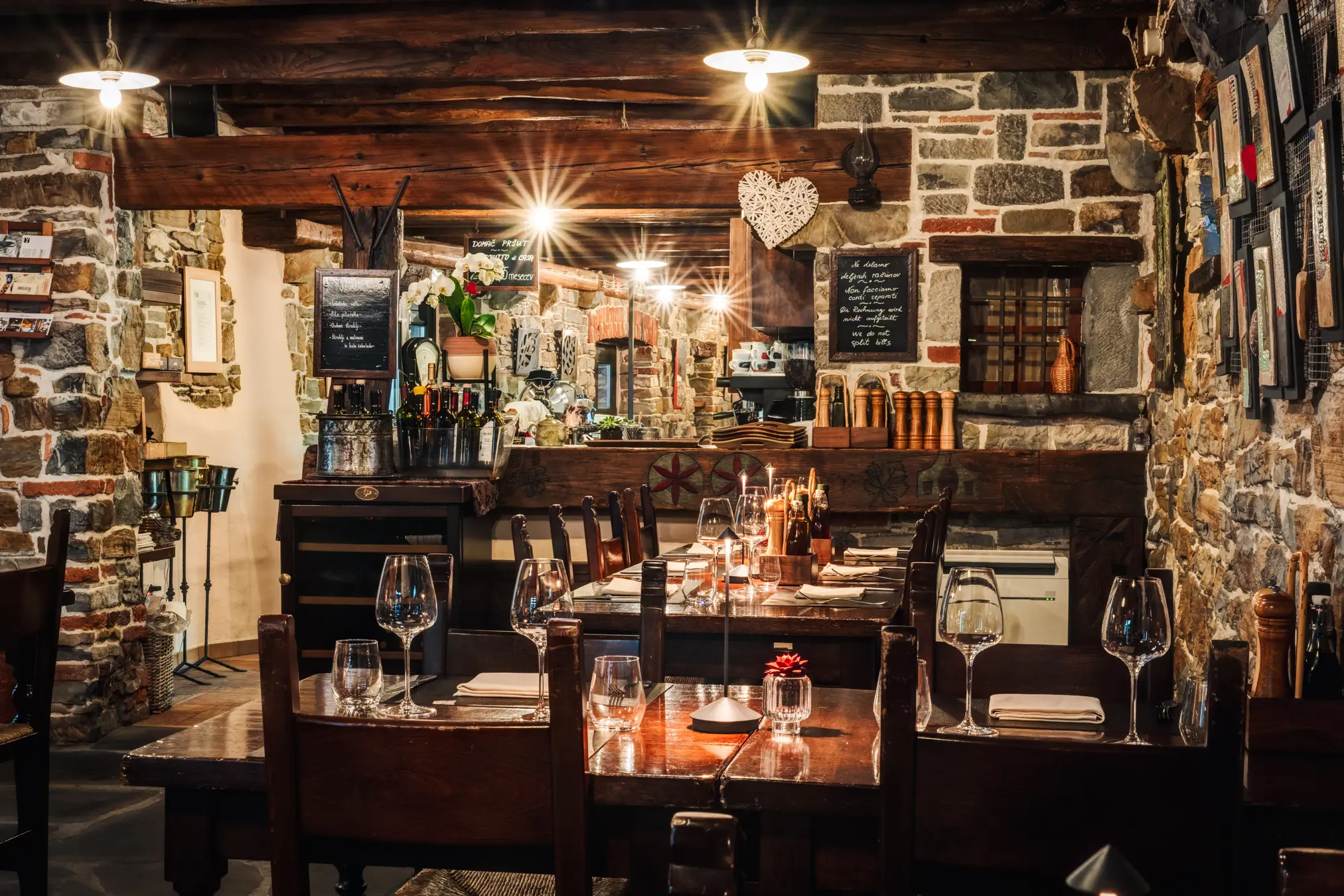 {"sl":"Notranjost restavracije z lesenimi stropi, kamnitimi stenami in mizami, pripravljenimi za goste.","en":"","de":"","it":""}