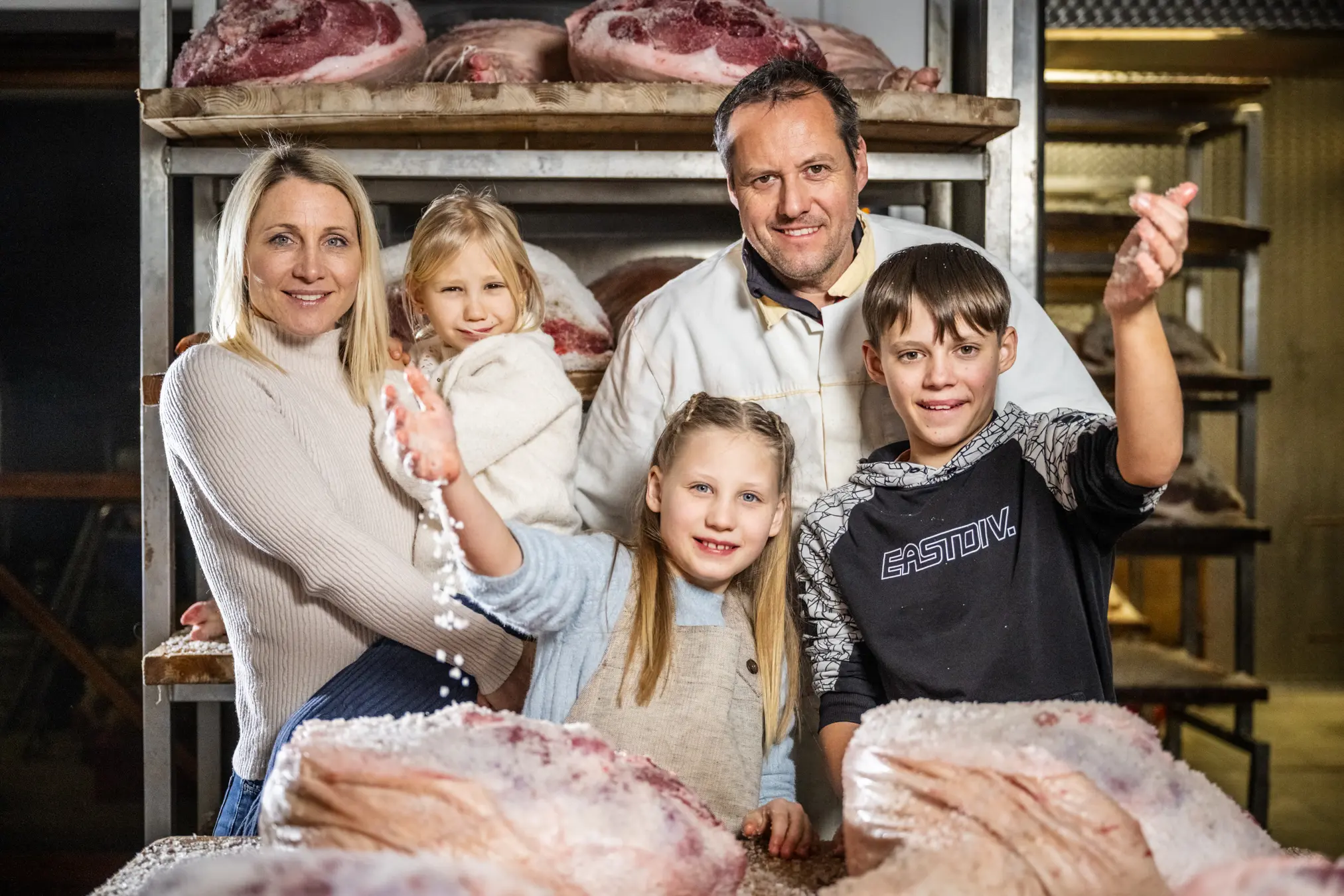 {"sl":"Dru\u017eina stoji pred policami, nalo\u017eenimi z mesom v su\u0161ilnici. \u017denska dr\u017ei otroka, drugi otrok se igra s soljo nad mesom.","en":"","de":"","it":""}